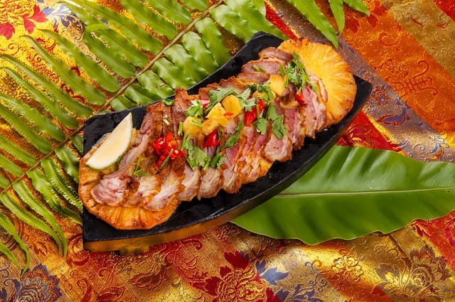 「薑黃烤豬頸肉」選用油花分布均勻、彈嫩多汁的豬頸肉，佐以南洋風味的薑黃香料醃製，慢火炙烤，表皮微焦、肉香誘人。／台北凱撒大飯店提供